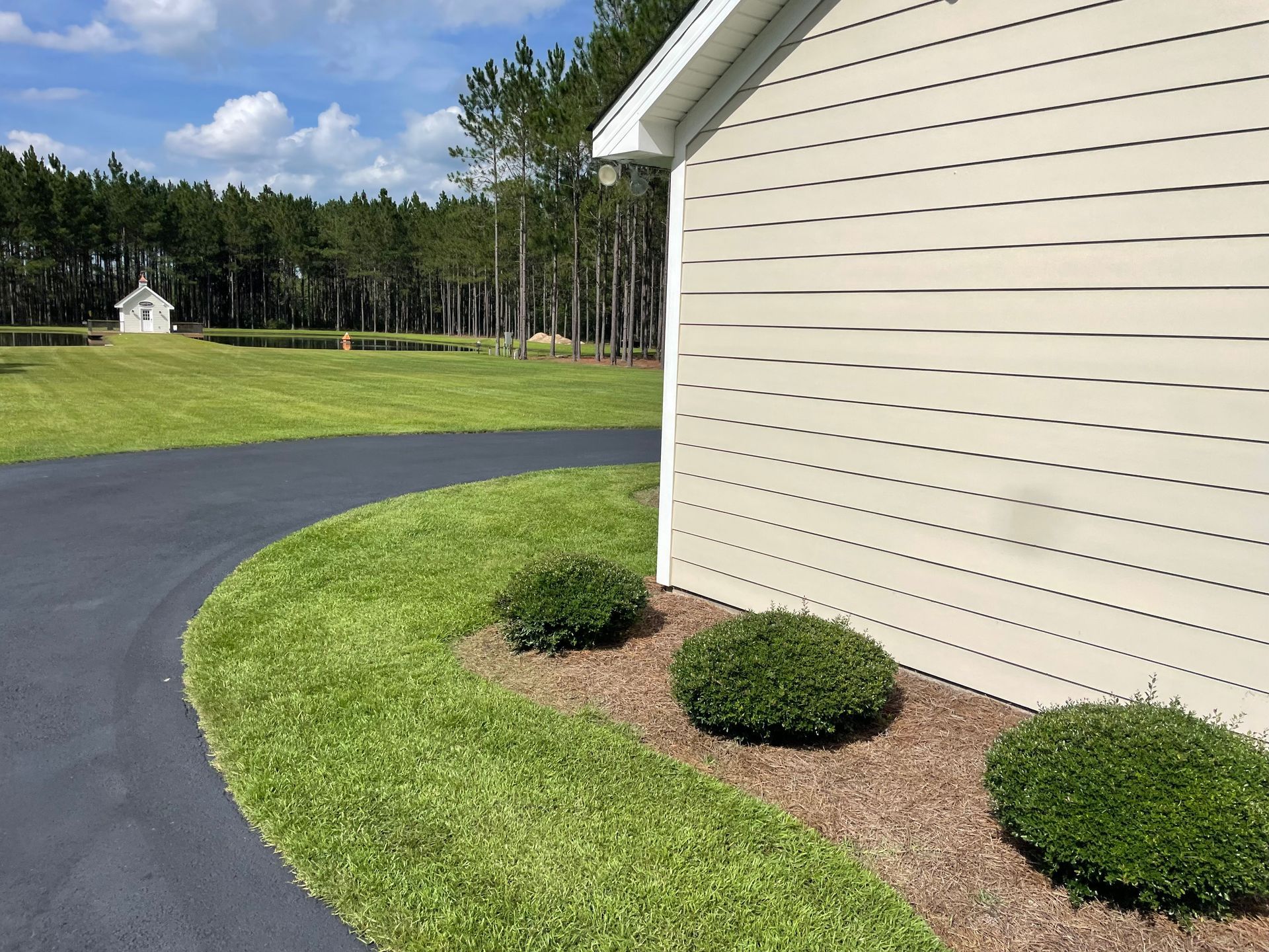 A house with a driveway and trees in the background