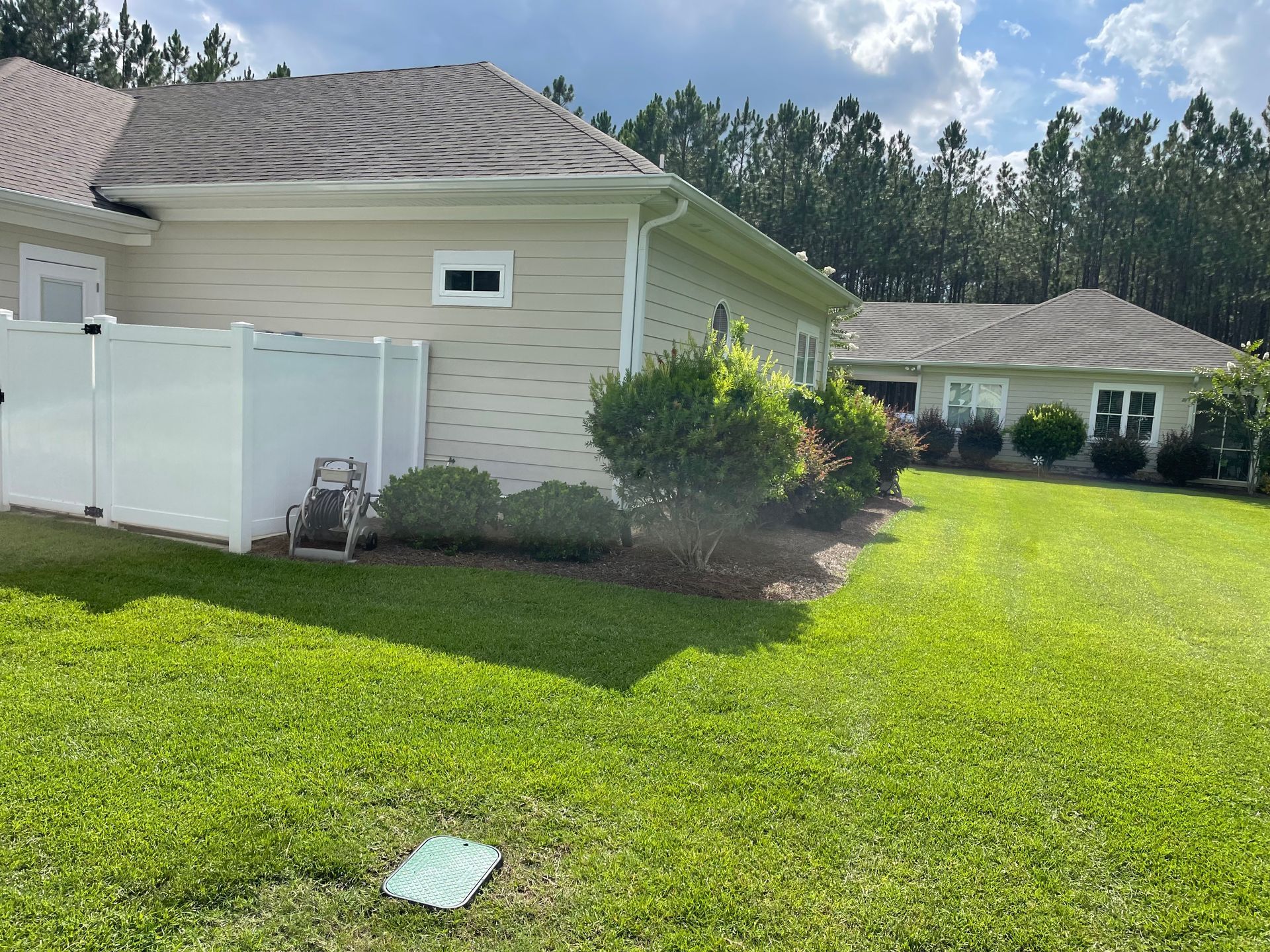 A house with a white fence and a large lawn in front of it.