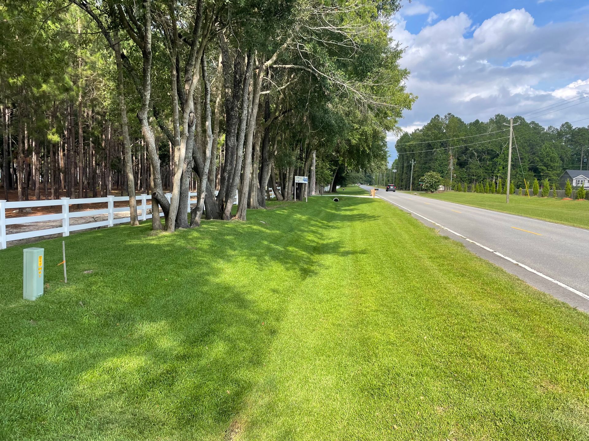 There is a white fence along the side of the road.