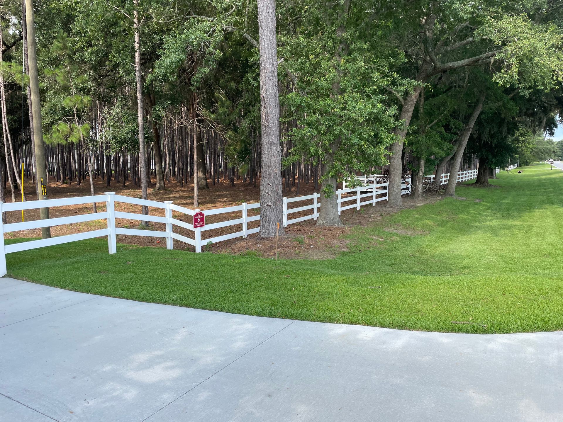 A white fence surrounds a lush green field.