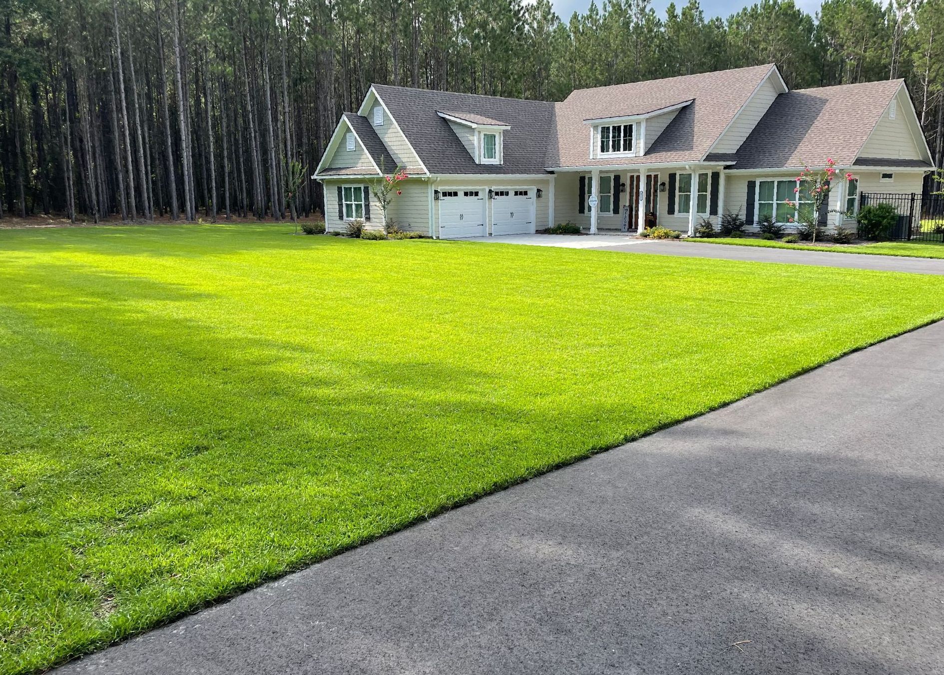 A large house with a lush green lawn and a driveway in front of it.