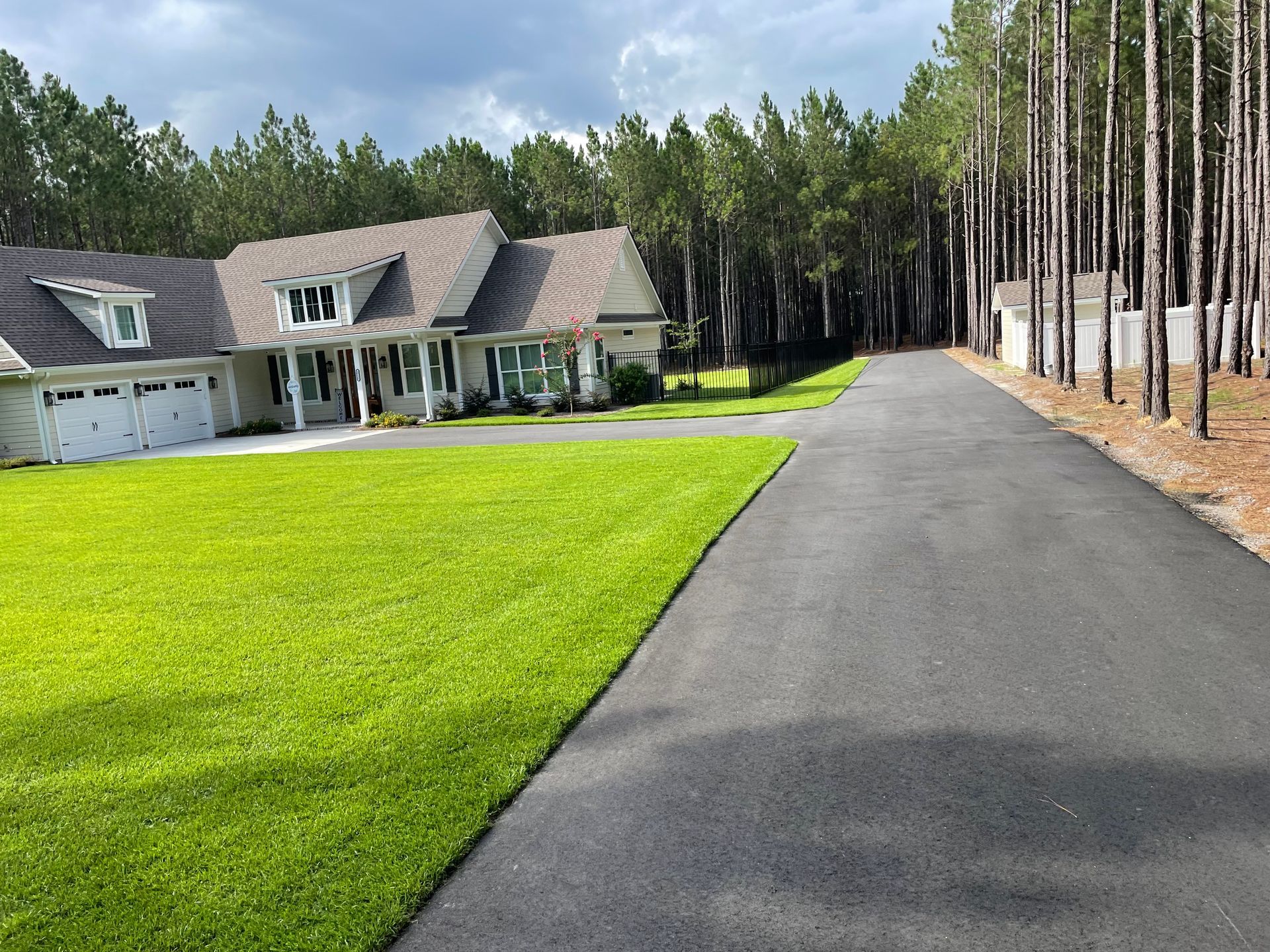 A driveway leading to a large house with a lush green lawn