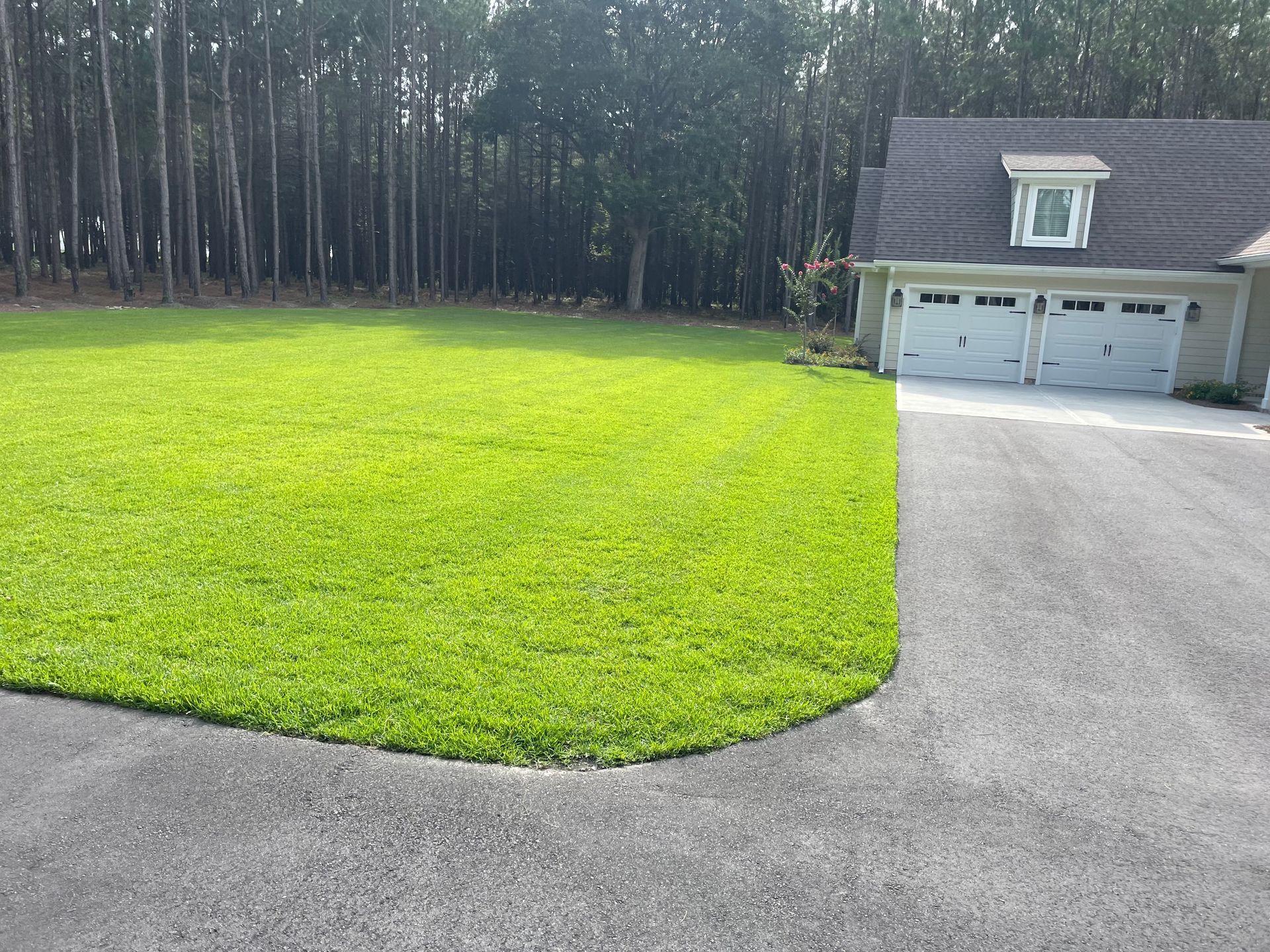 A house with a garage and a large lawn in front of it.