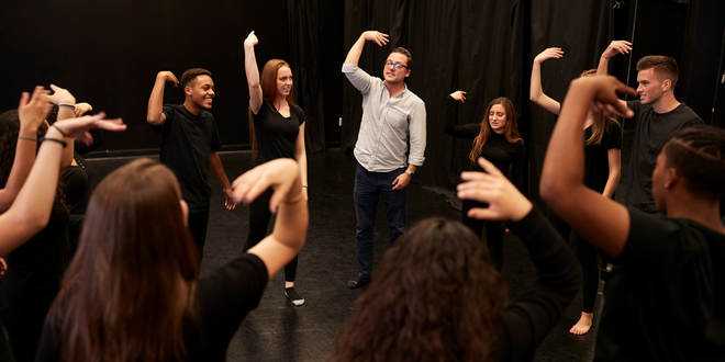 A group of people are standing in a circle with their hands in the air.