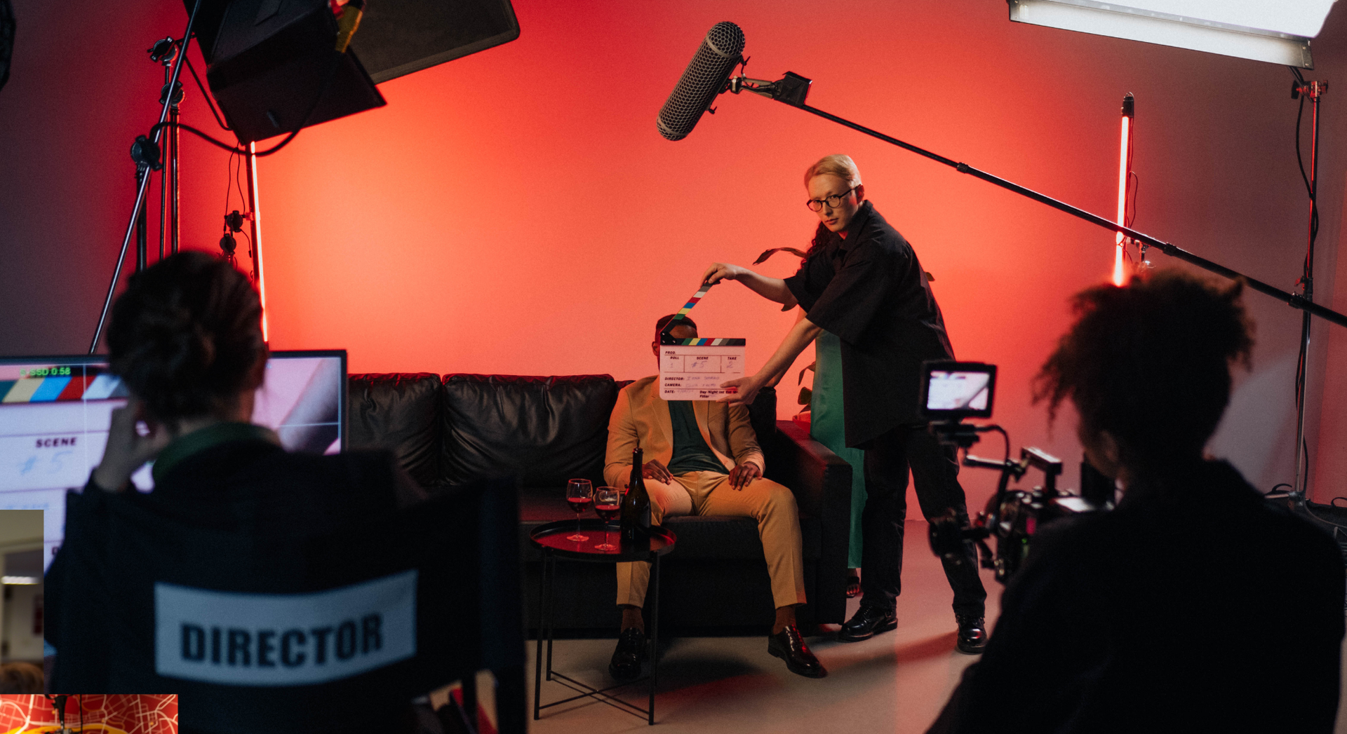 A director is sitting in a chair watching a man being filmed in a studio.