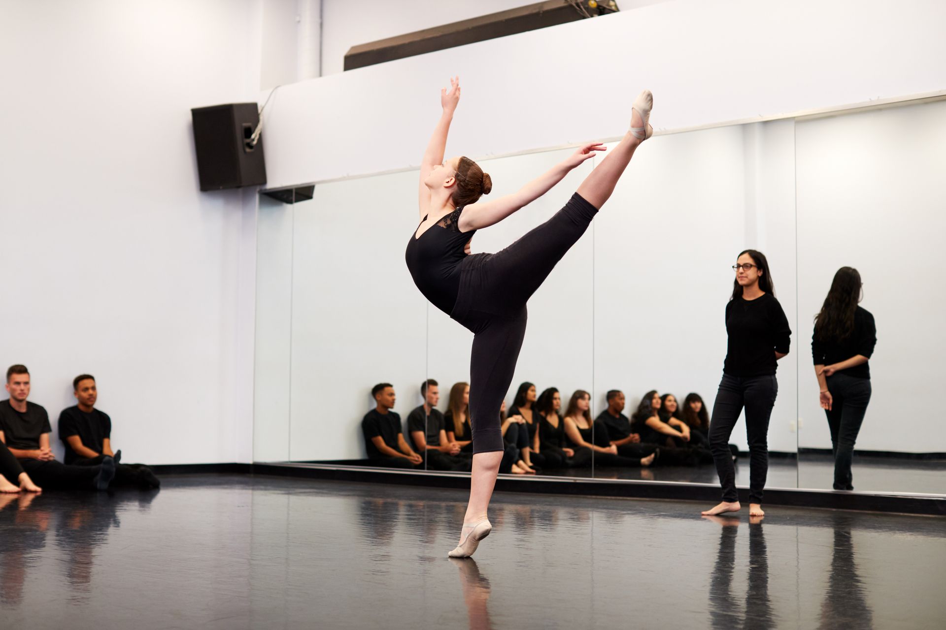 A woman is dancing in front of a group of people in a dance studio.