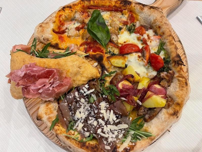 Pizza con zucchine, salsa cremosa, foglia di basilico, su un tavolo bianco.