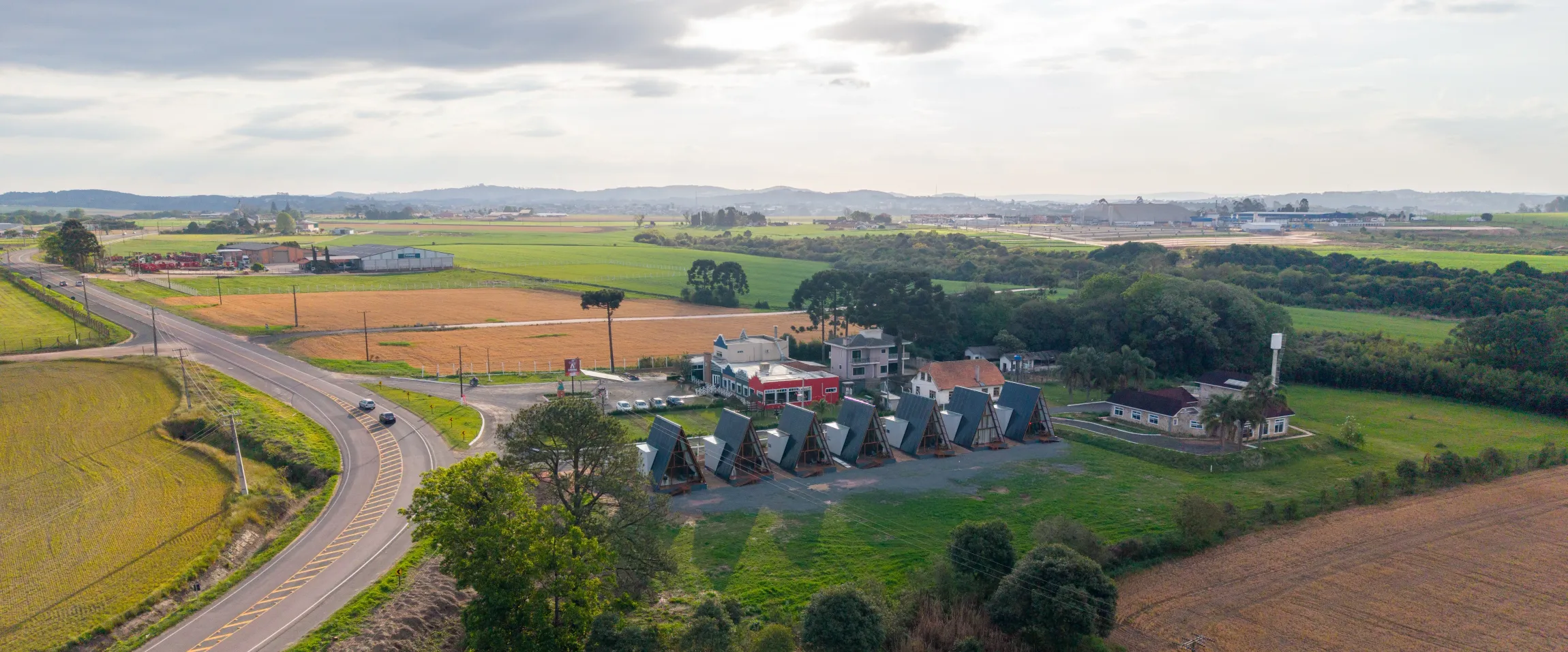 Vista aérea de uma estrada serpenteando por terras agrícolas com um grupo de pessoas. Chalé Mont Hermon.