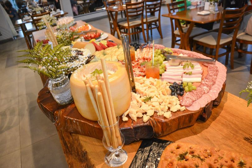 Uma tábua de frios de madeira cheia de queijo, carnes, frutas e palitos de pão, preparada para uma reunião. Chalé Mont Hermon.