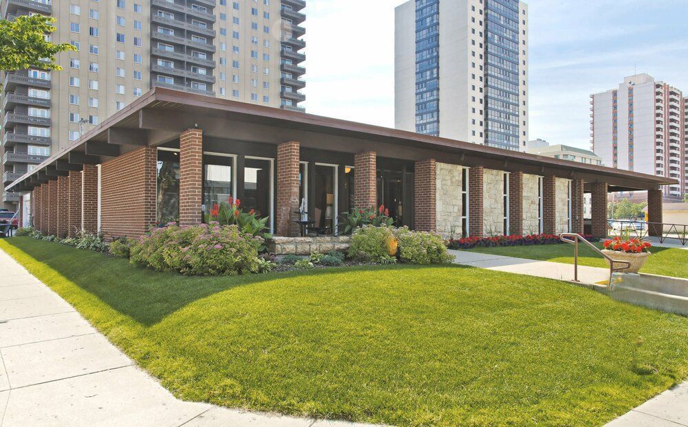 A large building with a lot of windows and a lush green lawn in front of it.