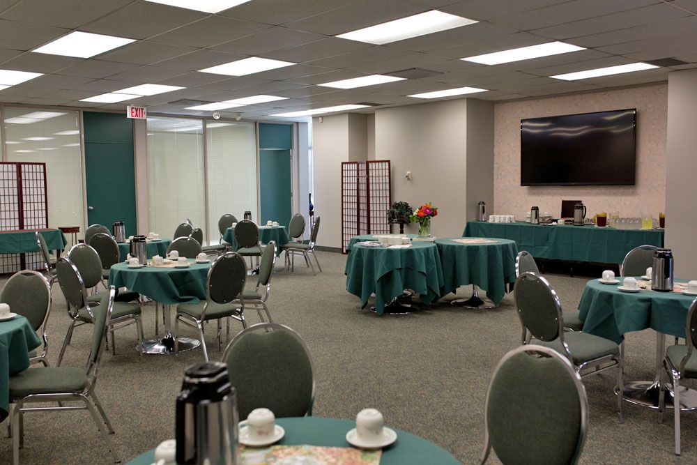 A large room with tables and chairs and a flat screen tv on the wall.