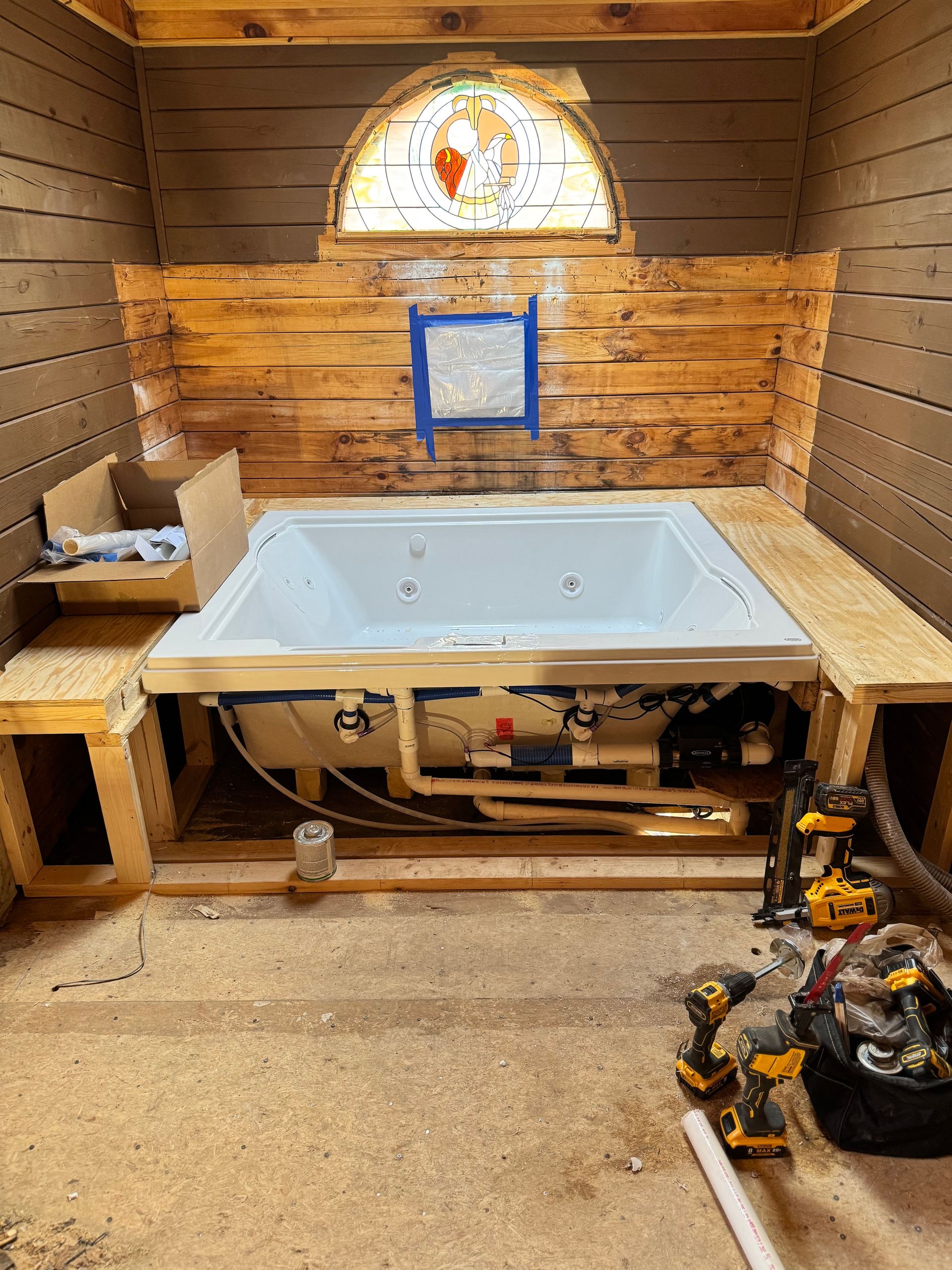 A partially built-in jacuzzi tub in a wood-paneled room, with tools scattered around.