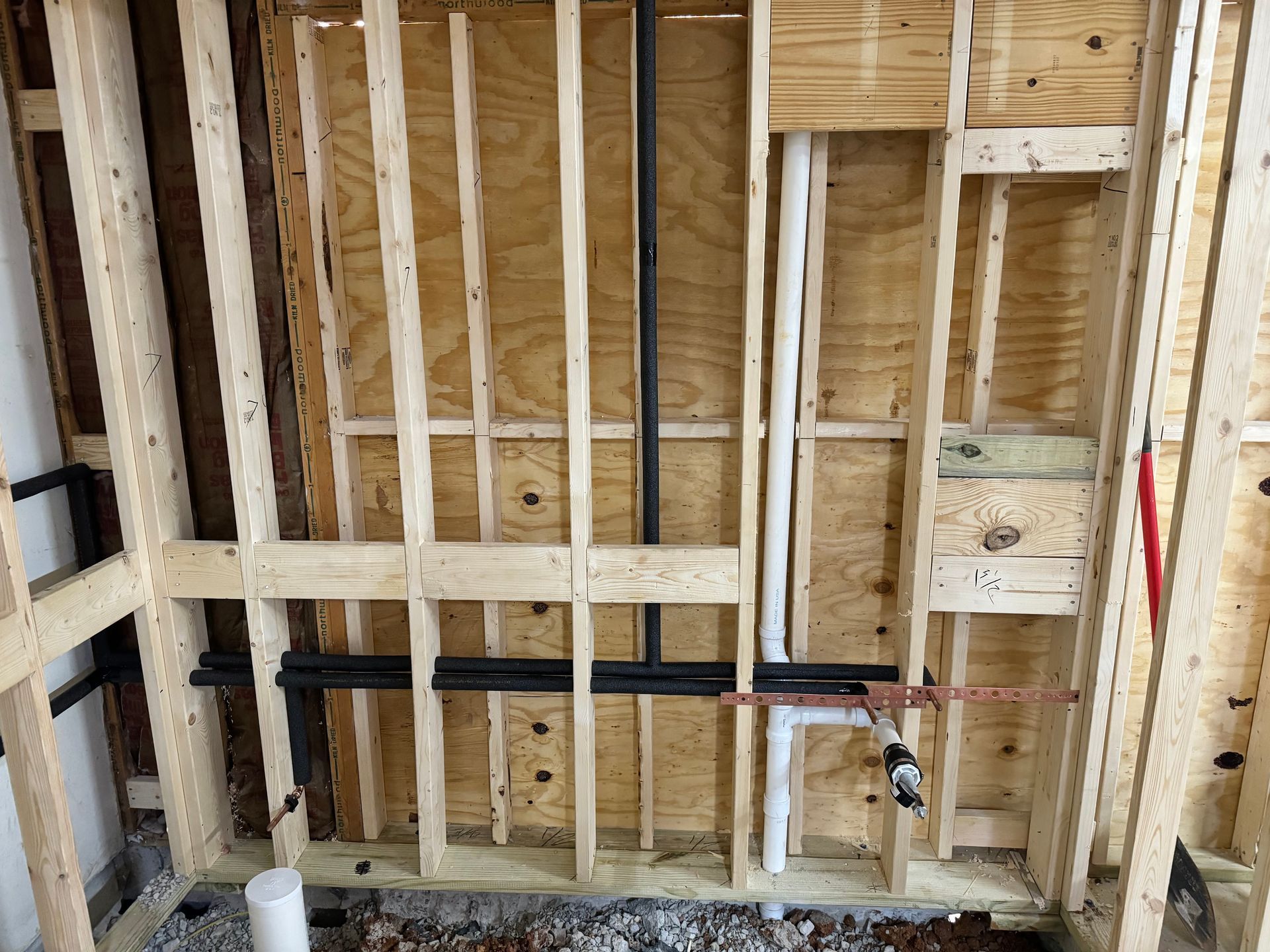 Wooden wall framing with pipes and plumbing visible.