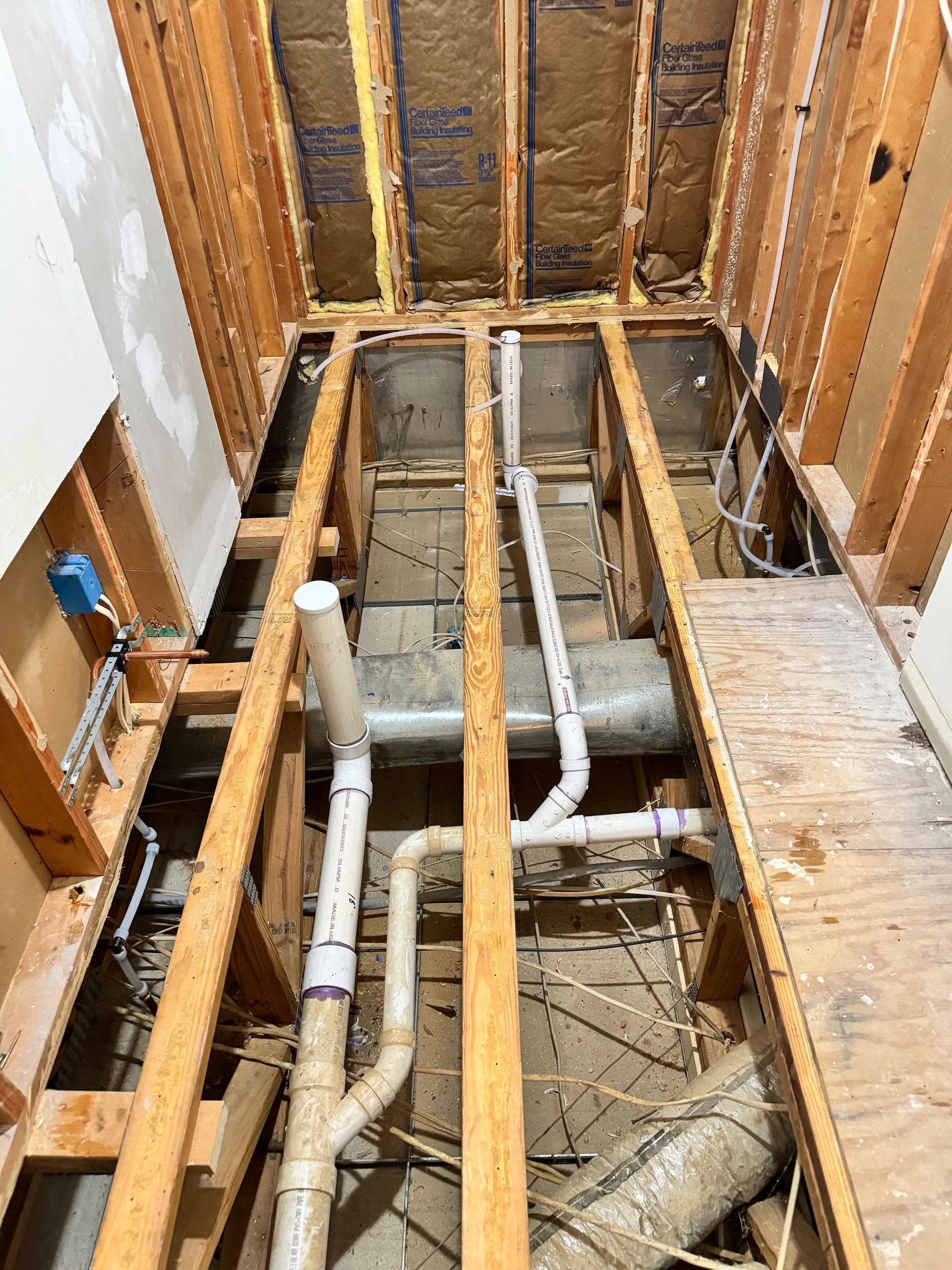 Framed bathroom renovation with exposed plumbing and ductwork.