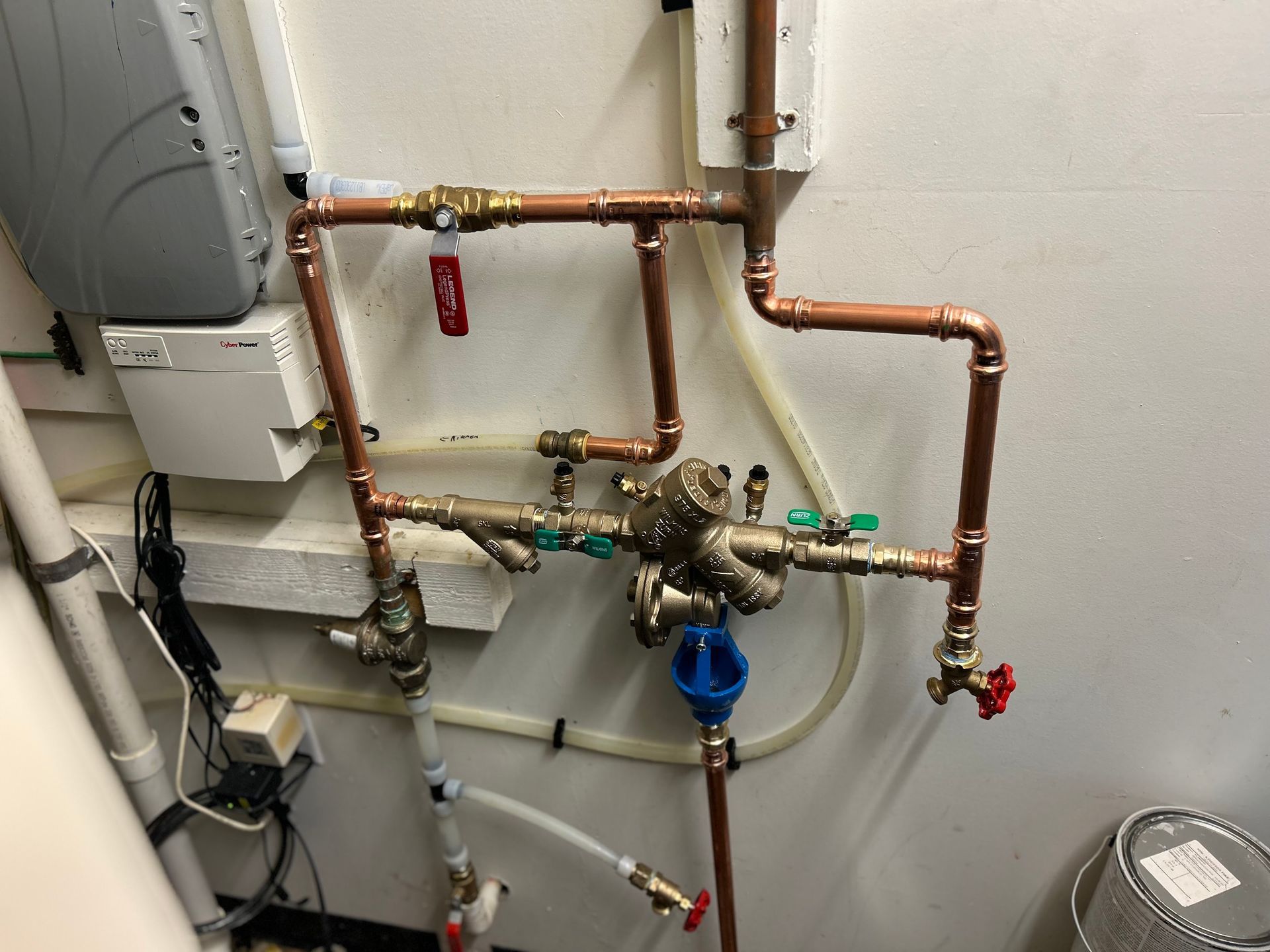 Copper pipes and valves against a white wall; part of a water system.