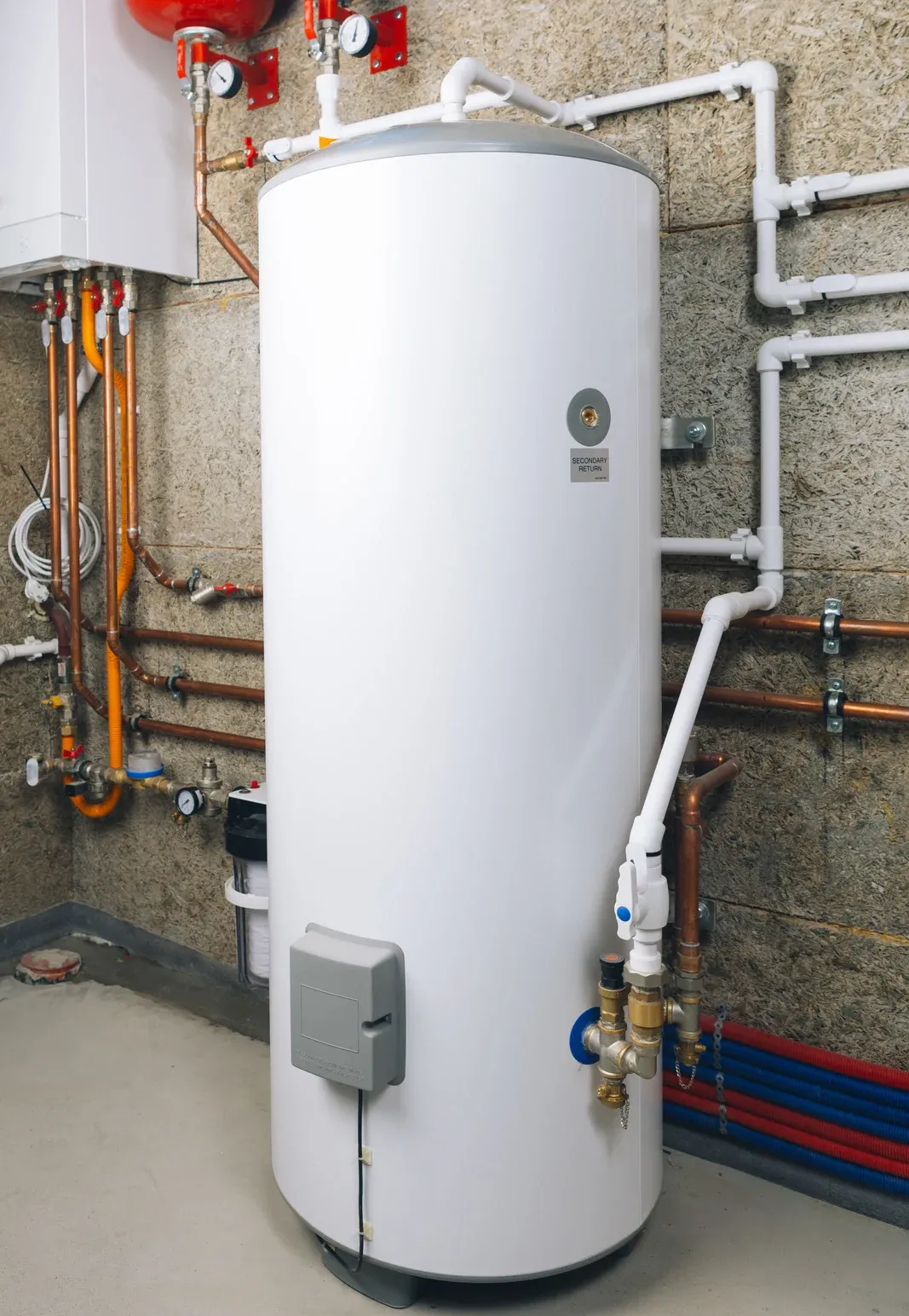 White water heater tank with connected pipes in a utility room, along with red, blue, and copper pipes.
