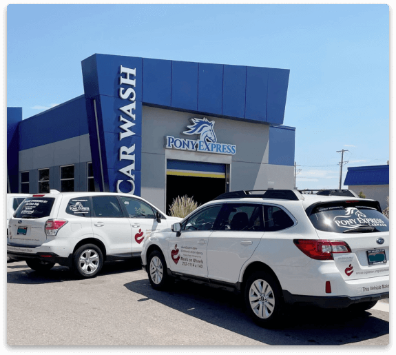 Two cars are parked in front of a car wash