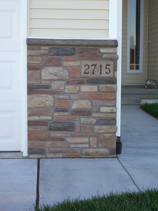 Stone column with house number 2715 beside a door and a sidewalk.