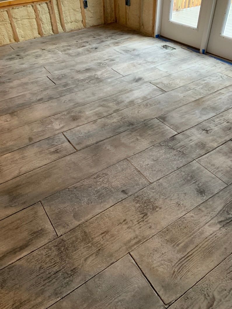 Wood-look flooring installed in a room with a window and partially constructed wall.