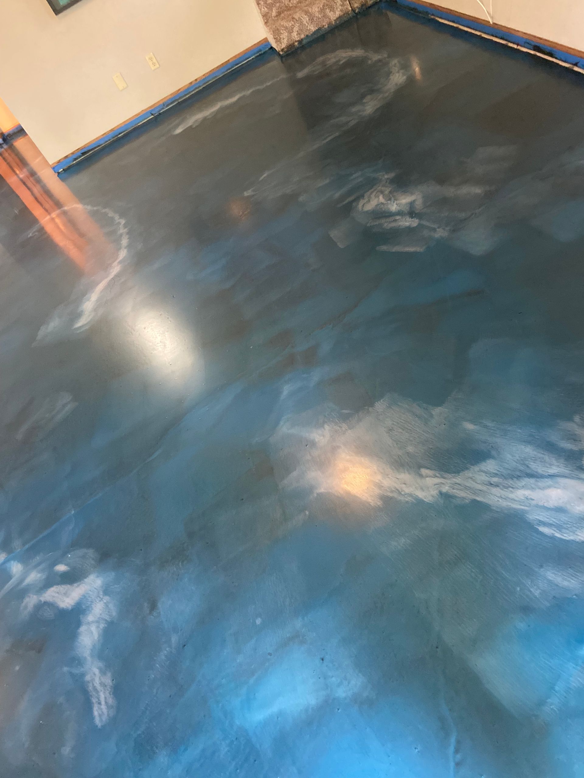 Metallic epoxy floor with blue and white swirls, reflecting light.