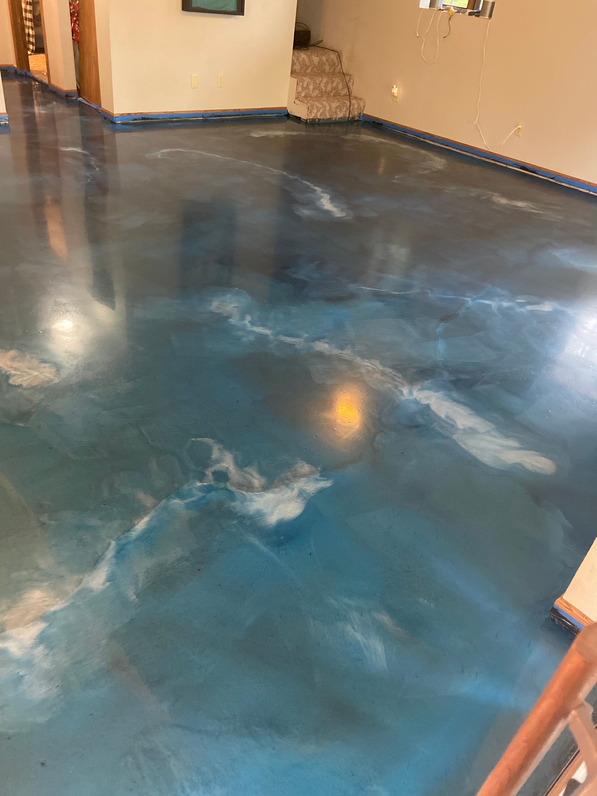 Blue and white swirled epoxy floor in a room, reflecting light.