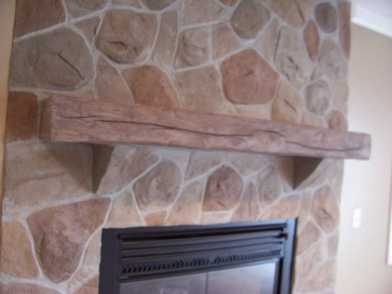 Fireplace with stone surround, dark fireplace insert, and wooden mantel.