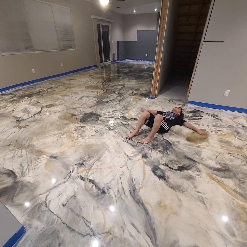 Man lies on a freshly poured, marbled epoxy floor in a room under construction.