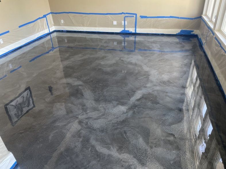 Metallic silver epoxy floor with blue tape along the walls of a room.