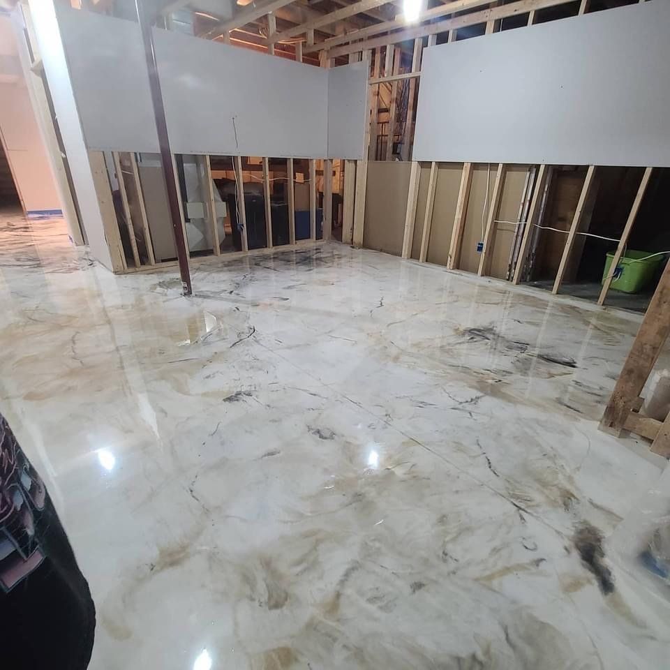Basement under construction with a glossy, marbled epoxy floor. Drywall partially installed. Wooden frame visible.