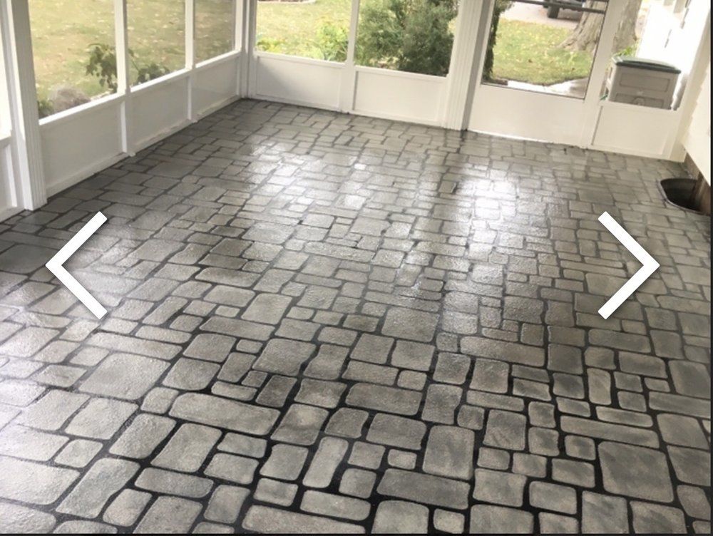 Gray stone patterned floor inside a sunroom with white walls and windows.