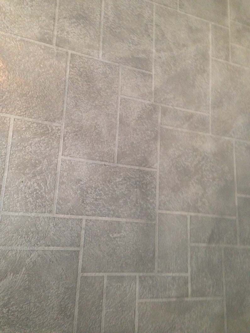 Gray rectangular tile floor with grout lines.