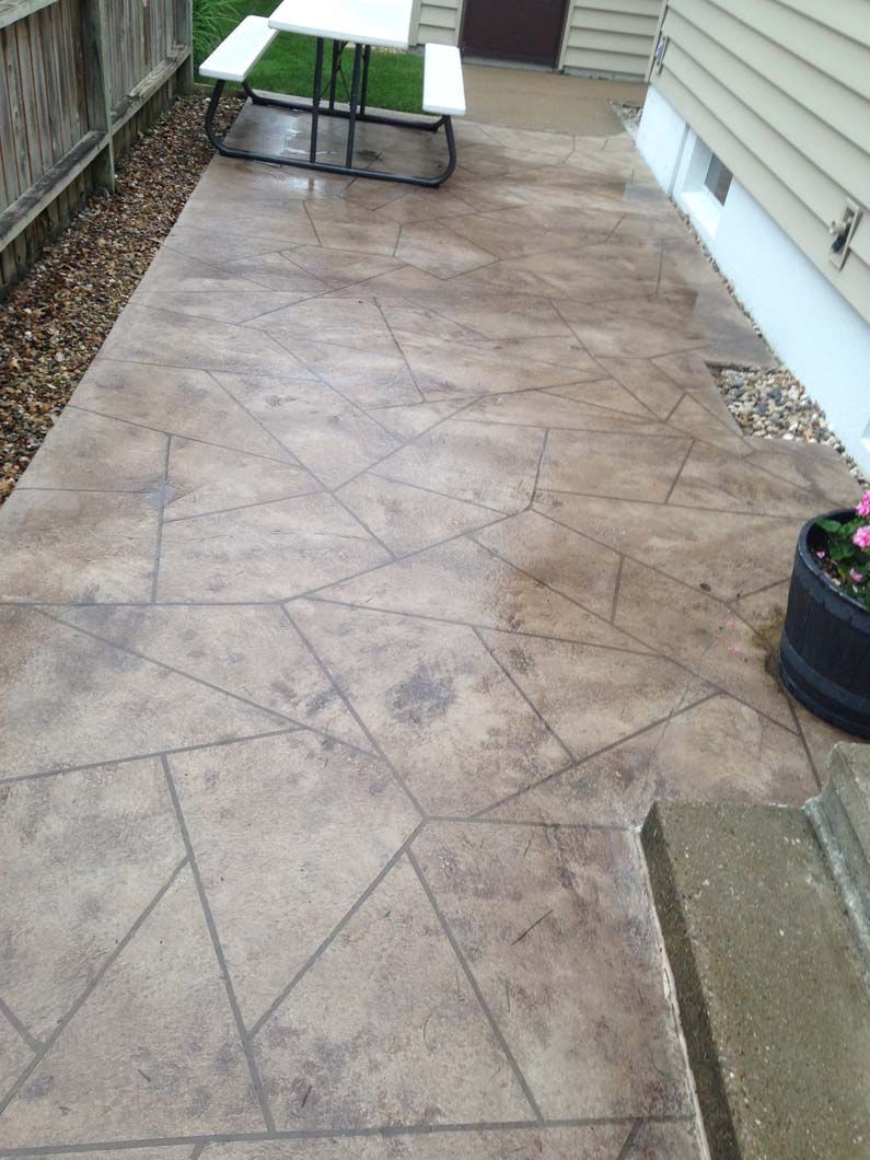 Stamped concrete patio with a geometric pattern. A picnic table and flower pot are visible.
