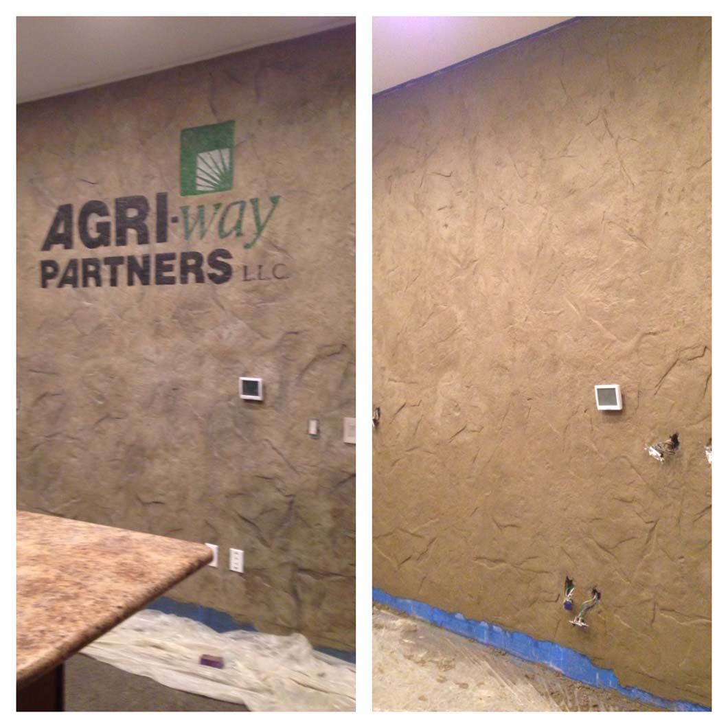 Two walls with a textured, brown finish. One has a business logo