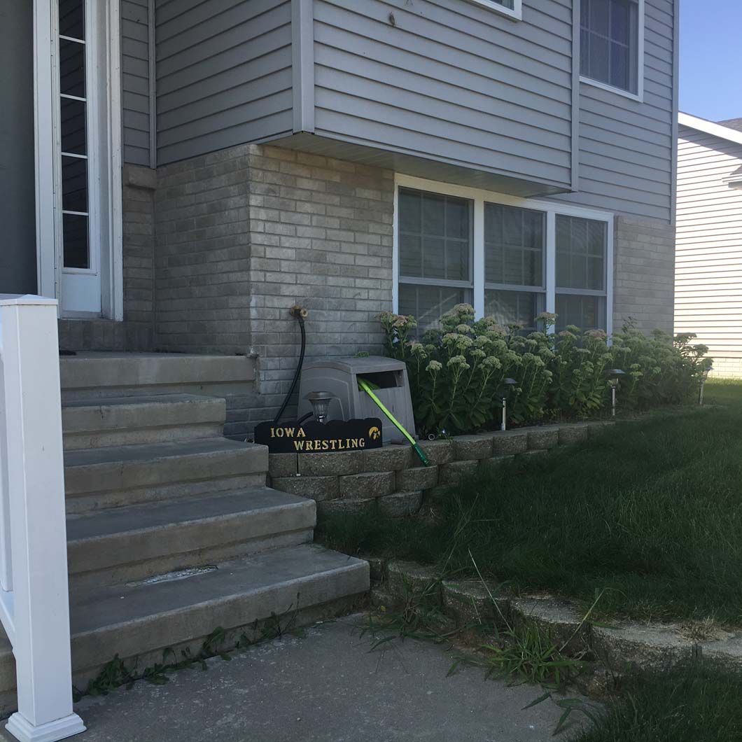 Gray house with steps, a door, window, and landscaping.