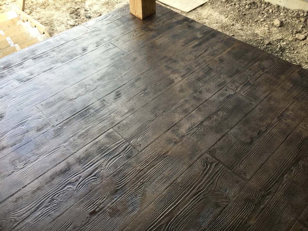 Dark brown wood-look concrete floor with textured grain pattern.
