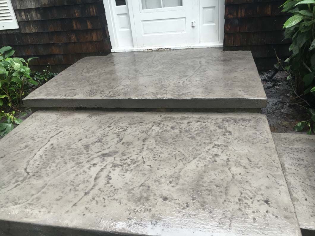 Gray concrete steps leading up to a white door.