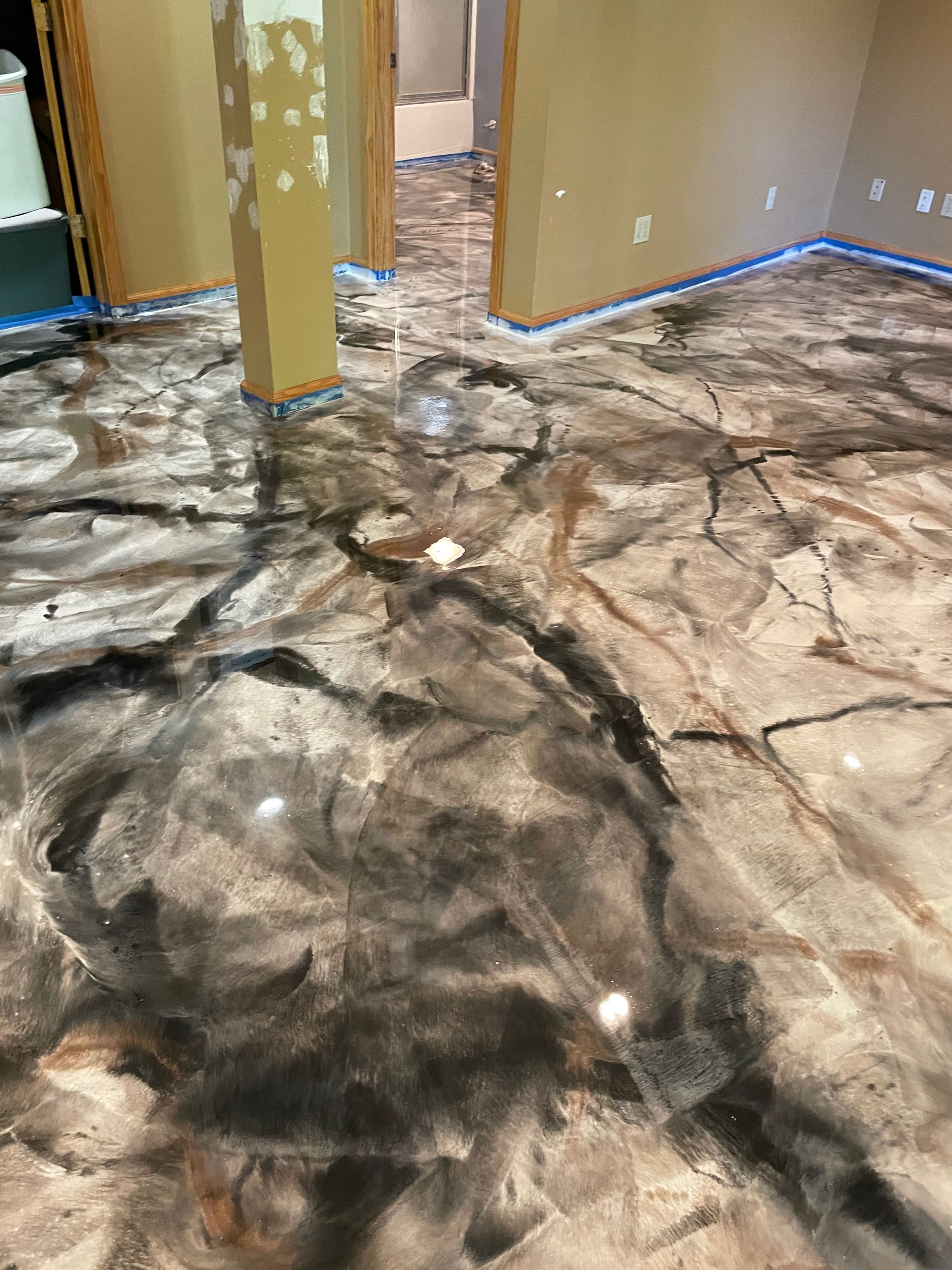 Metallic epoxy floor with black, silver, and bronze swirls in a room.