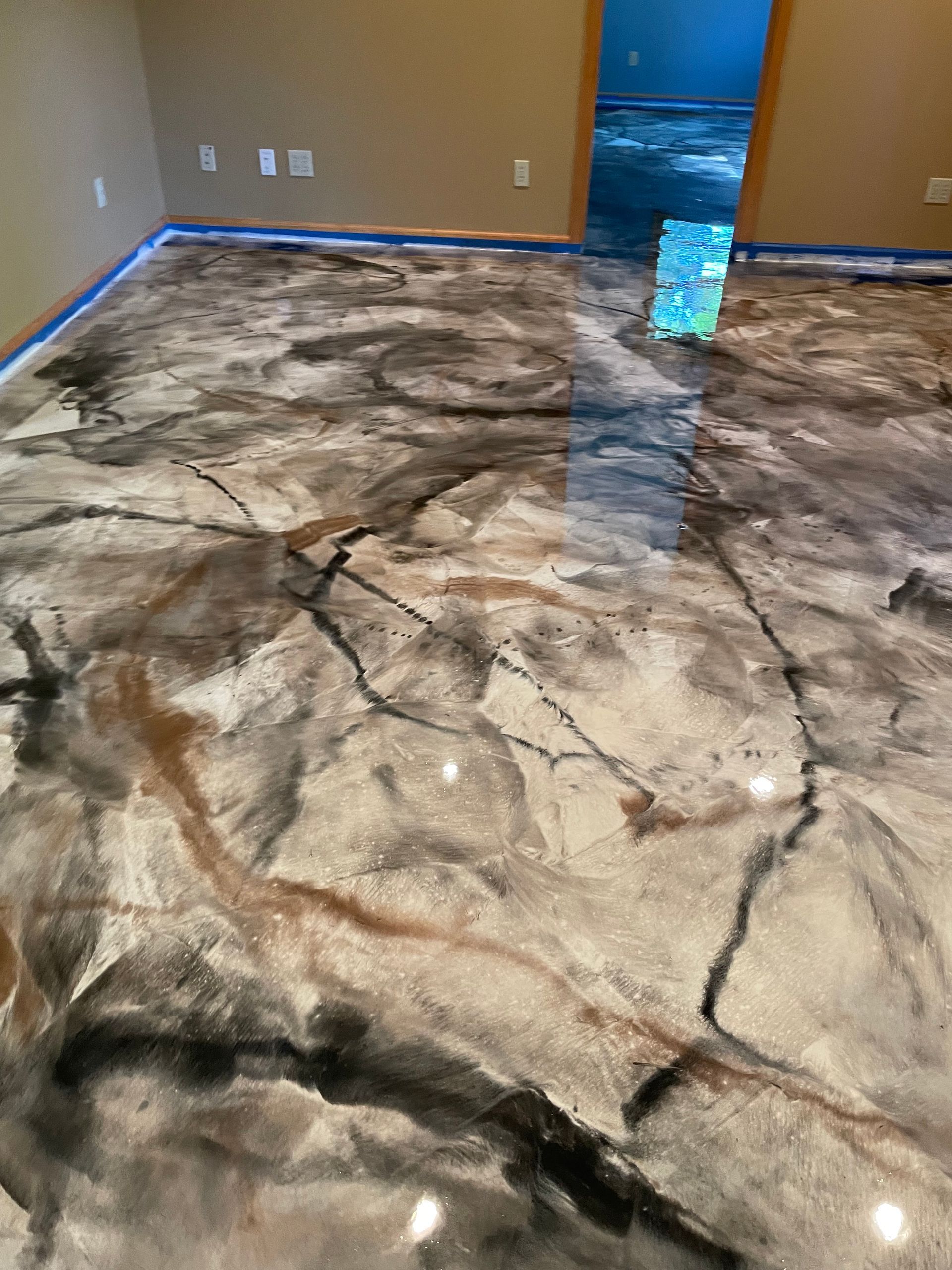 Metallic epoxy flooring with black, bronze, and silver swirls.