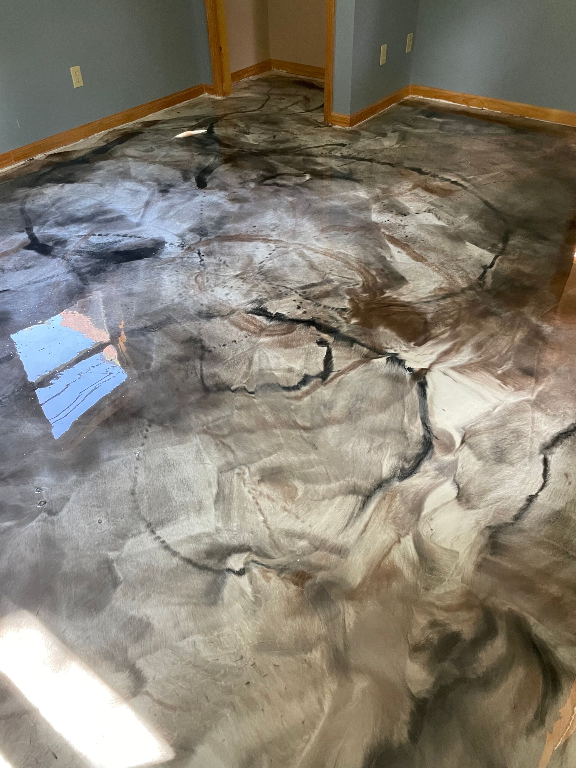 Metallic epoxy floor with brown, gray, and black swirls, resembling cracked marble in a room.