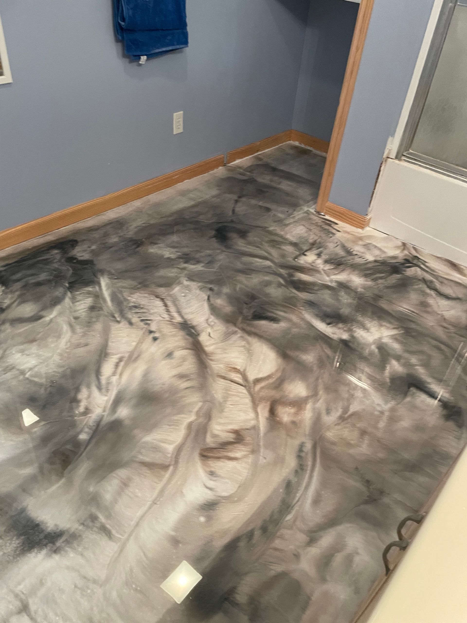 Bathroom with metallic epoxy flooring in shades of gray, black, and white.