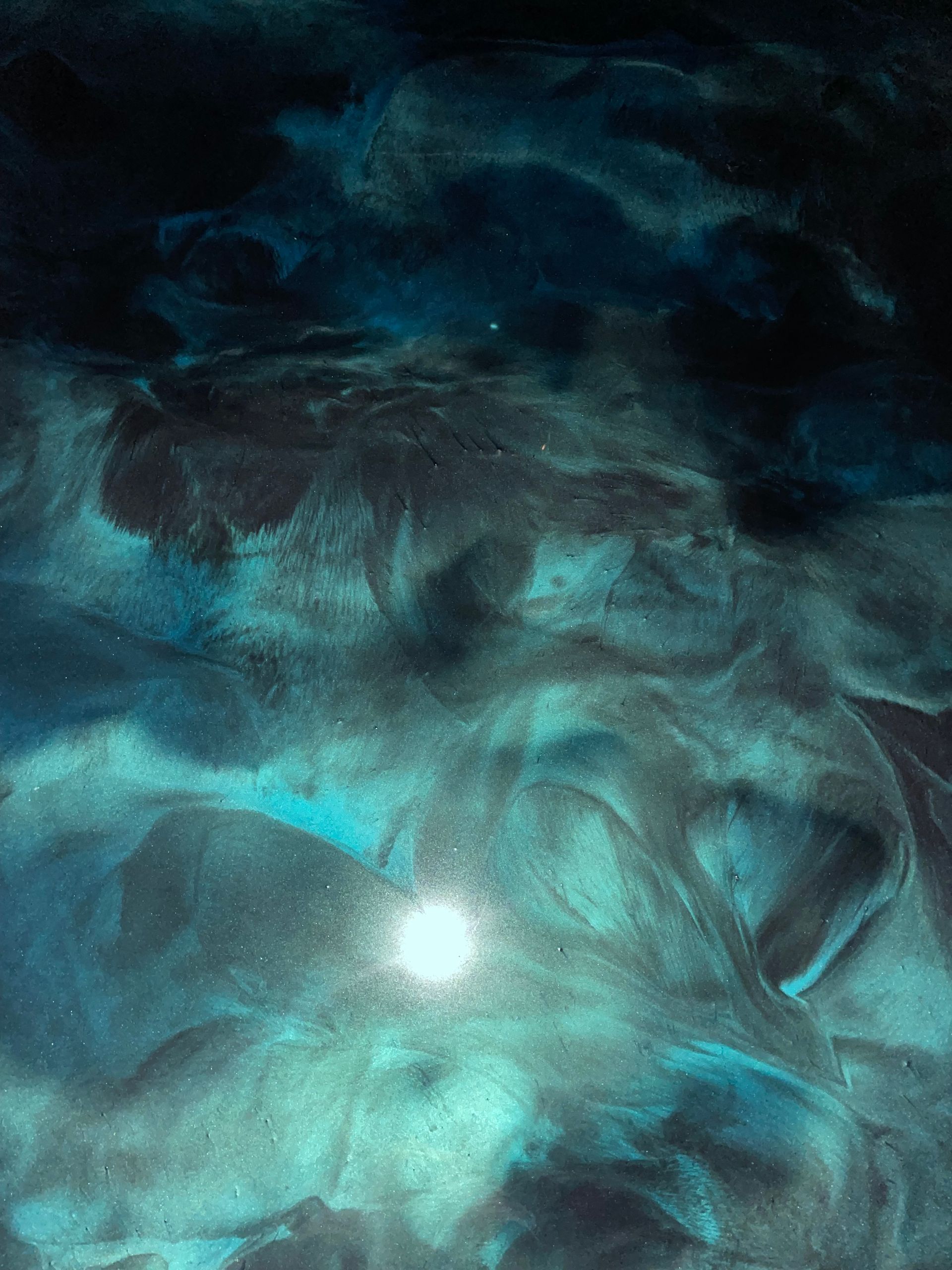 Abstract turquoise and black swirls with a bright, glowing center, resembling a nebula or cosmic scene.