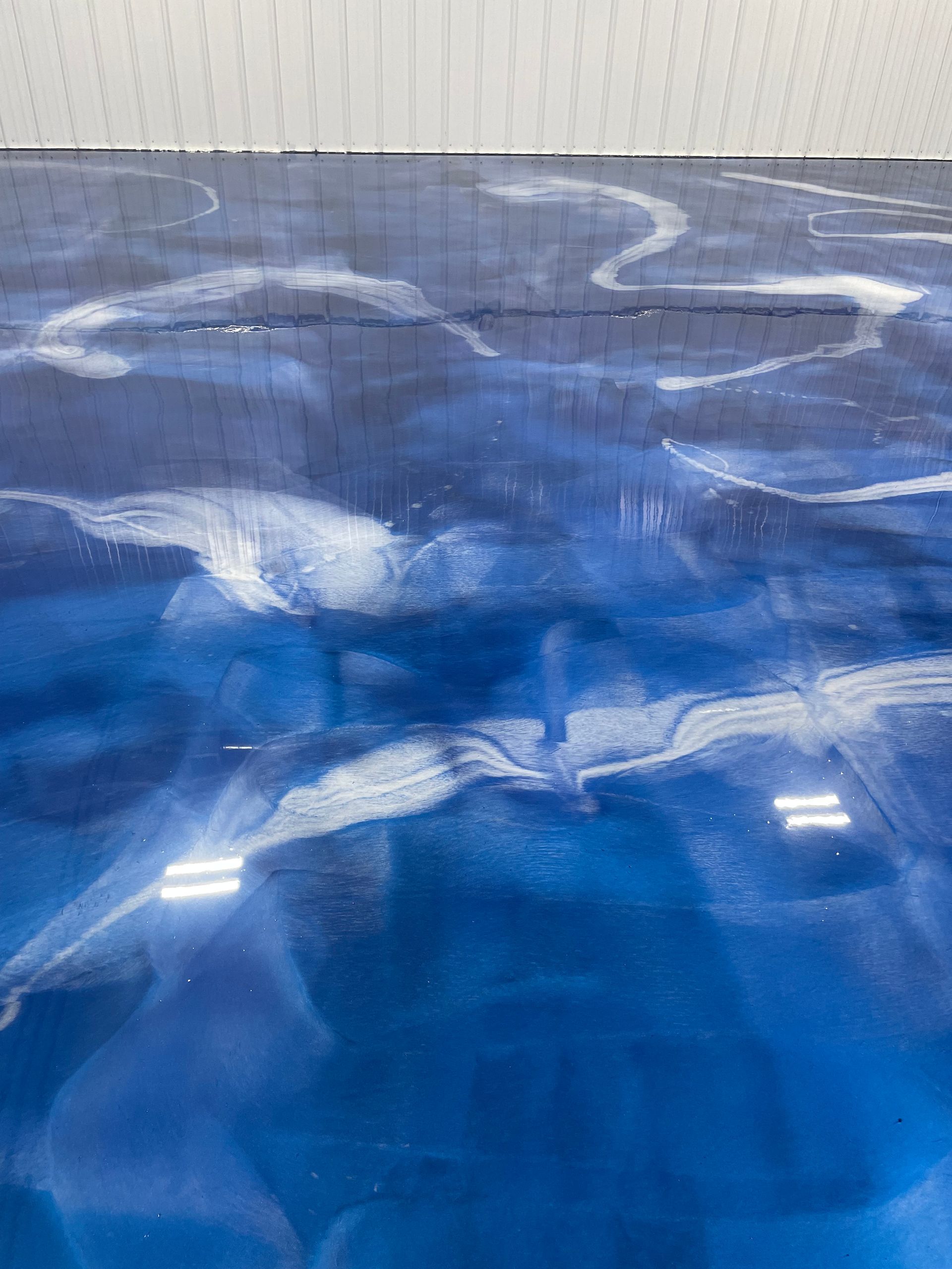 Blue epoxy floor with white swirling patterns reflecting light.