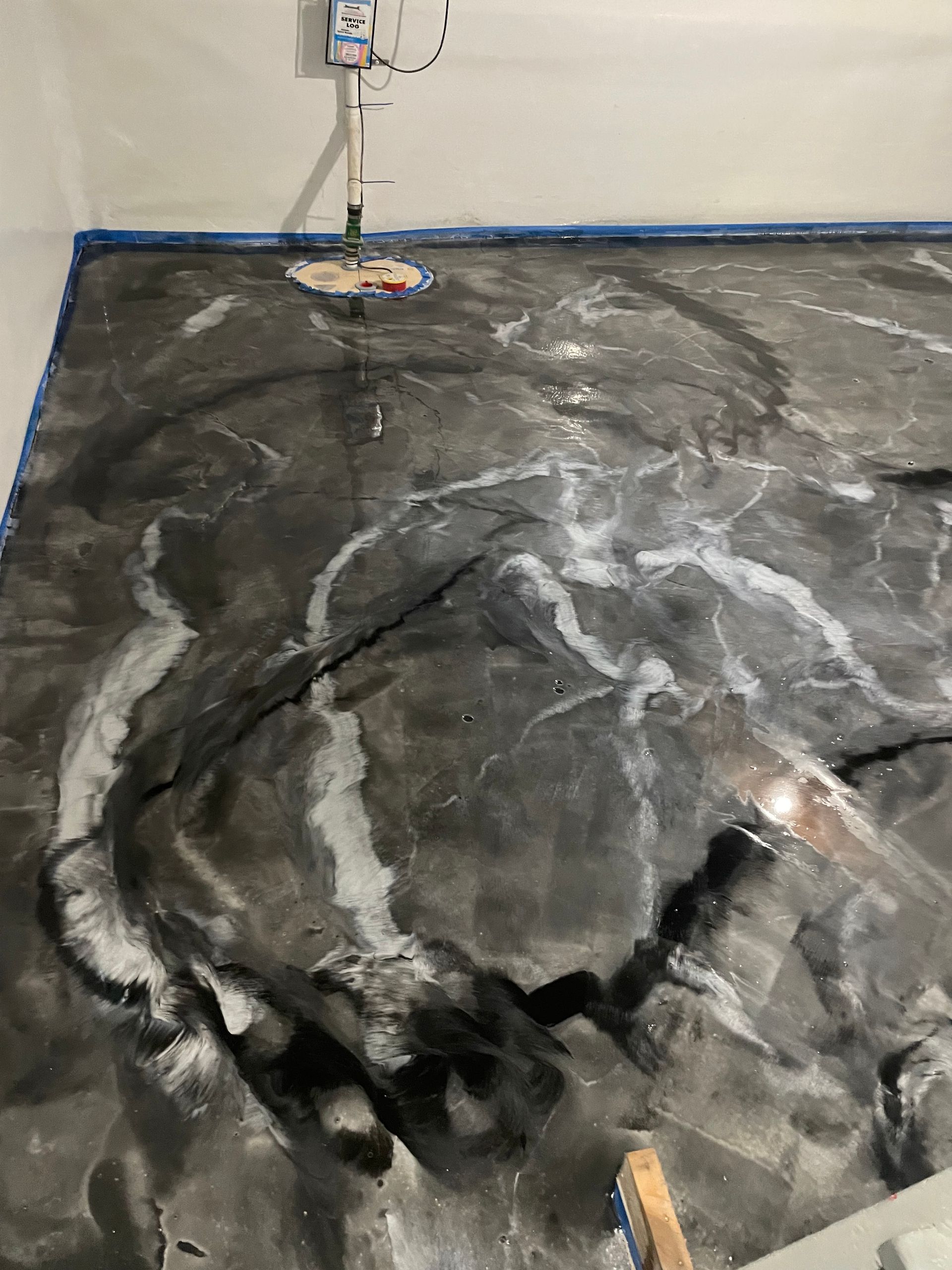 Epoxy-coated floor with marble design, black and white swirls. Sump pump visible, gray setting.