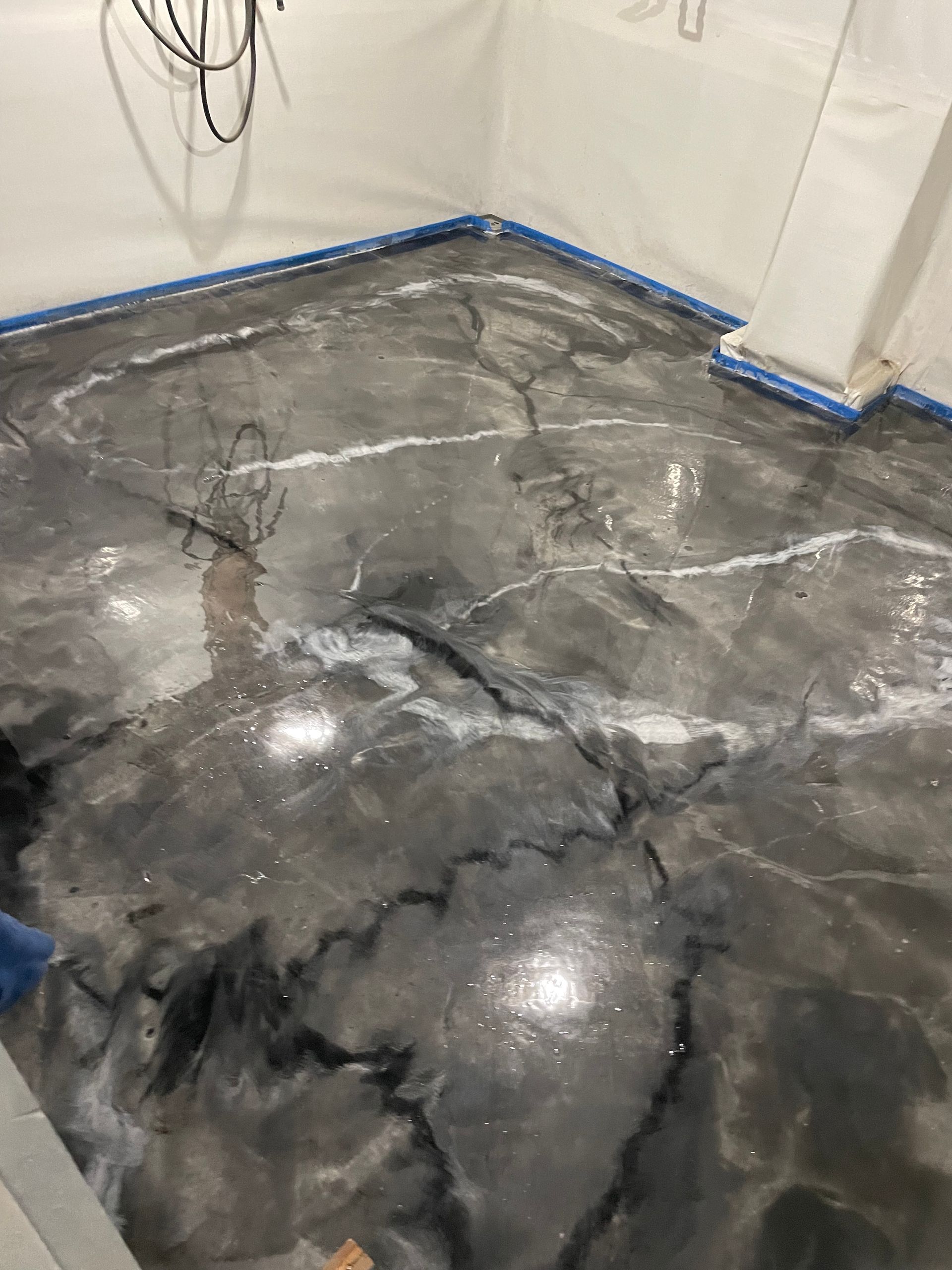 Metallic gray epoxy floor with white and black veining, newly installed in a room with white walls.