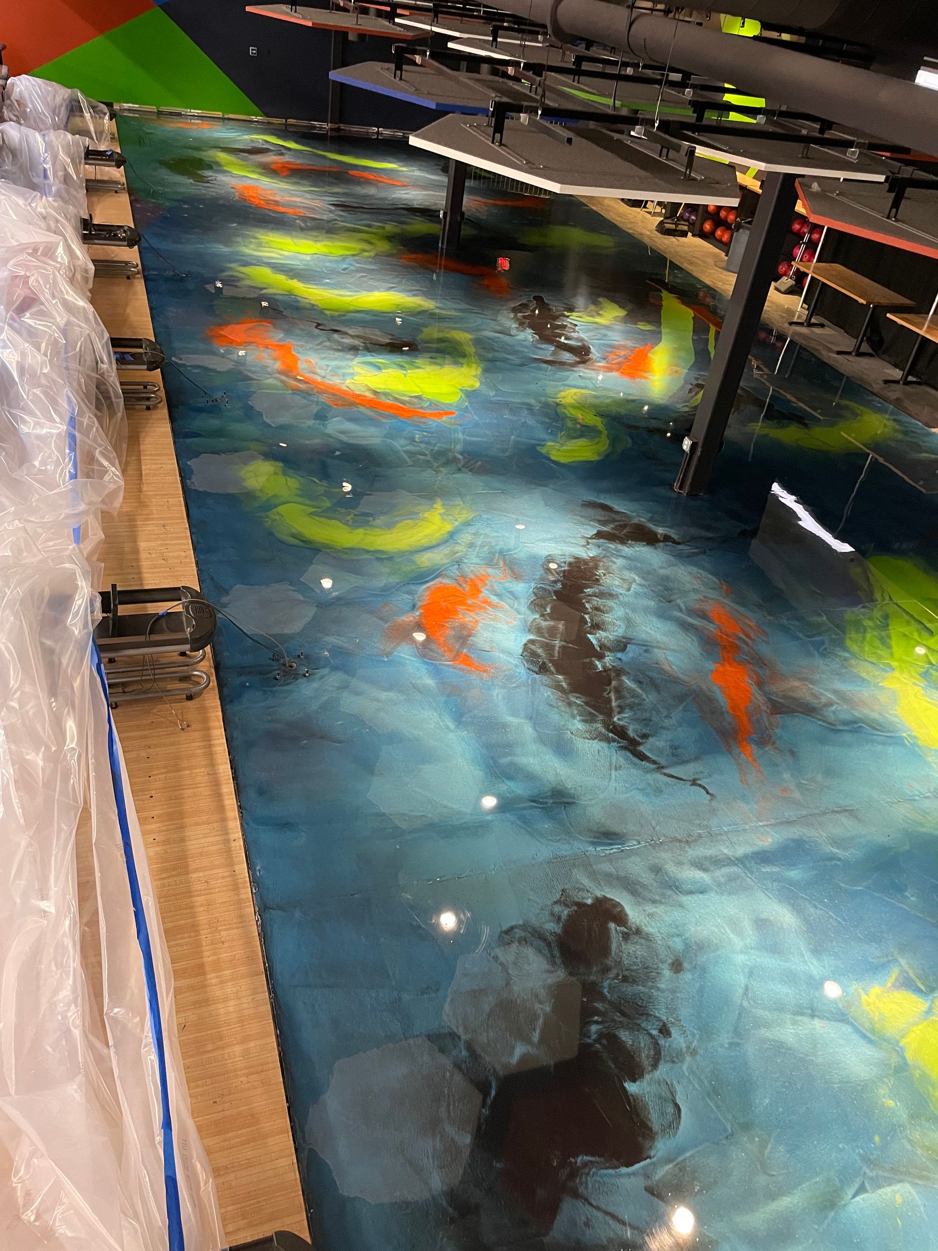 Metallic epoxy floor with blue, orange, and yellow swirls, resembling a colorful river, indoors.