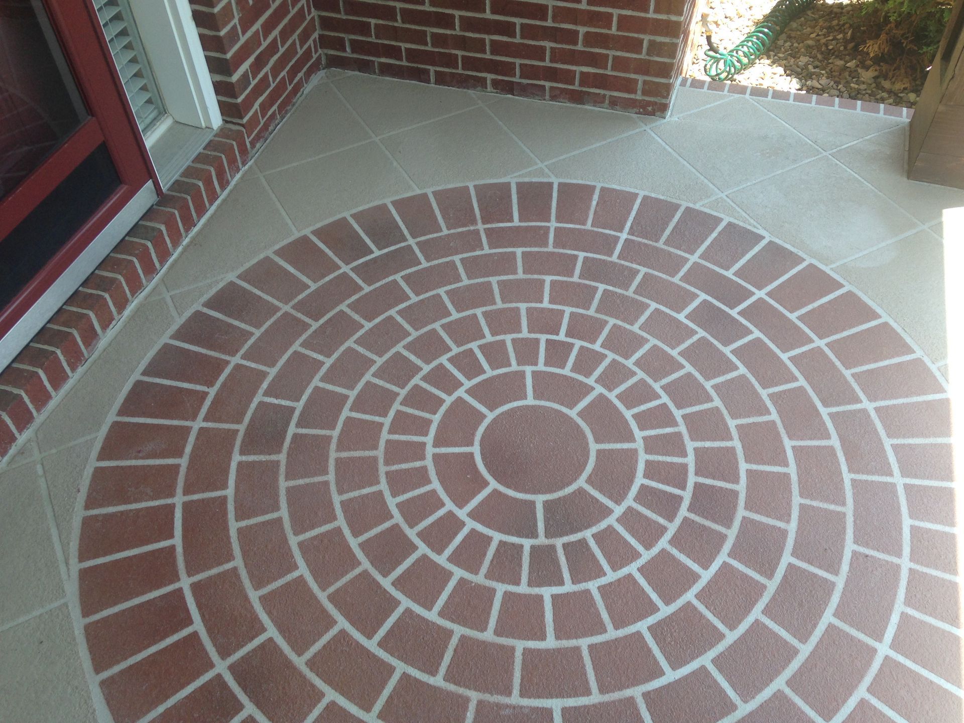 Brick and tan tiled patio with a circular brick pattern.