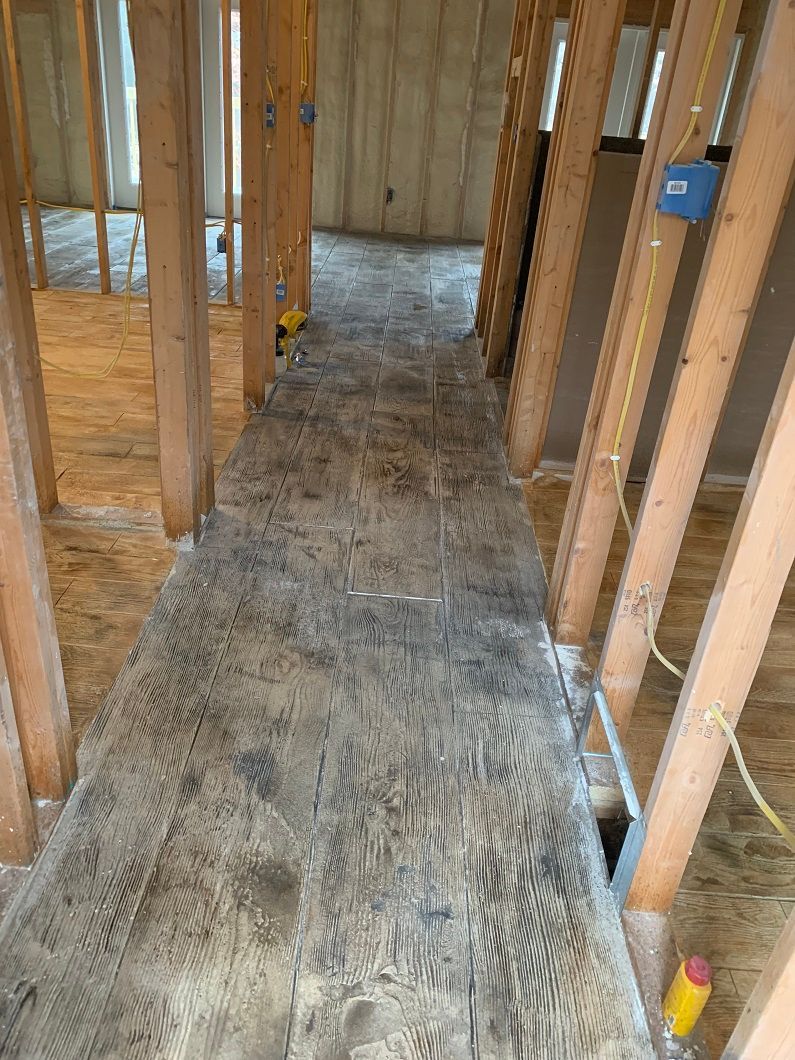 Construction site interior with exposed wooden beams and subflooring in a hallway.