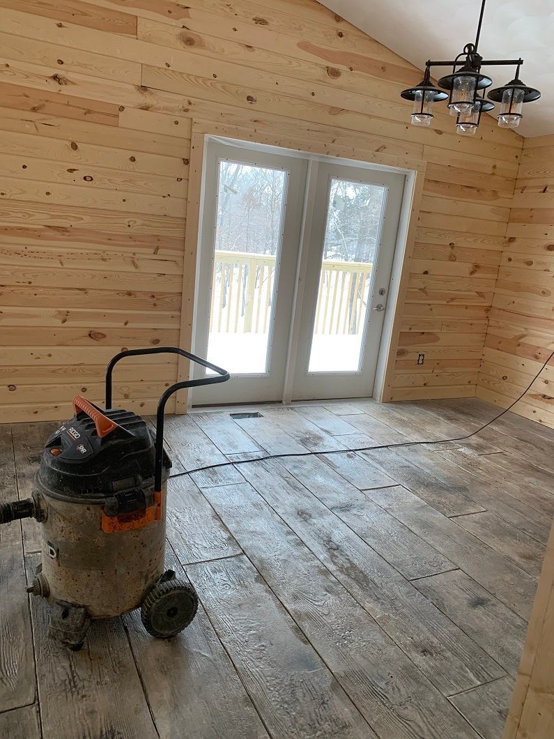 Interior of a room with wood walls, French doors, and a shop vacuum on a wood-look floor.