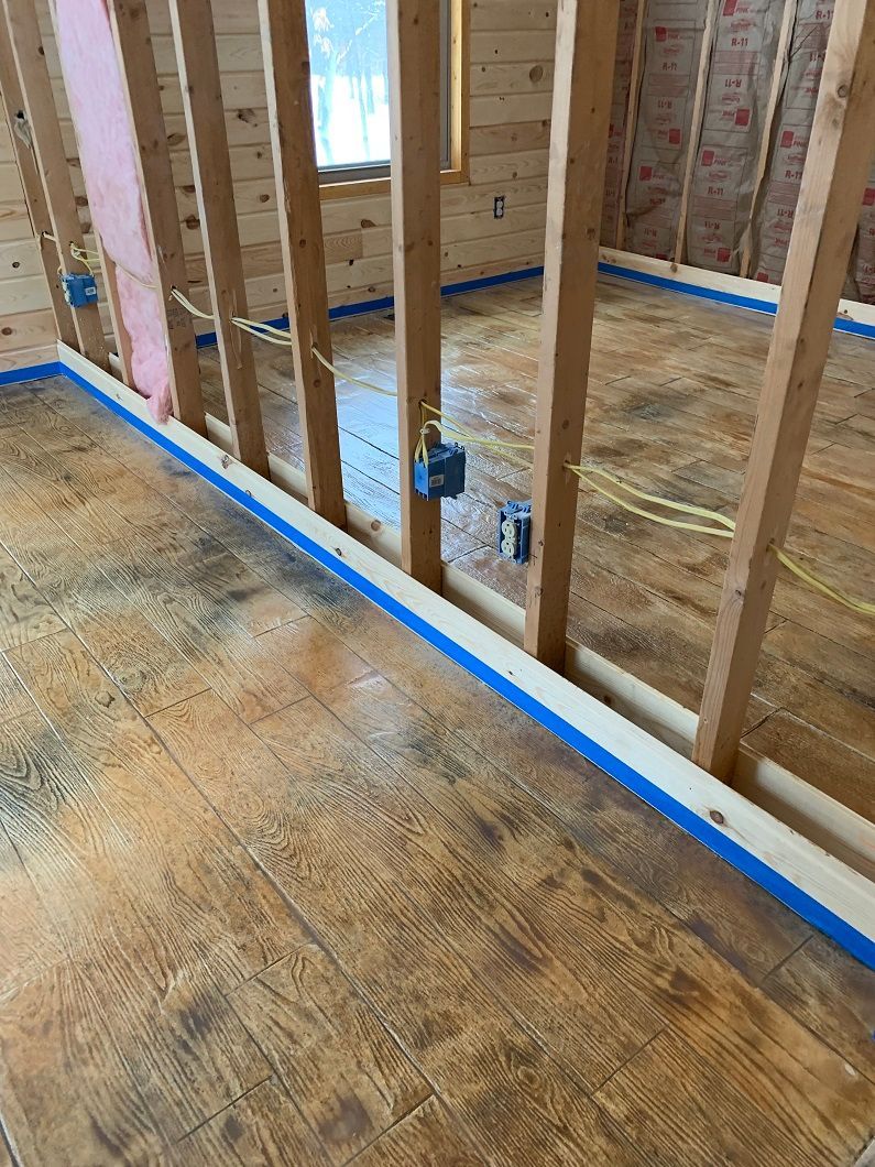 Interior construction: wooden frame, exposed electrical wiring, blue tape along floor, wooden flooring.