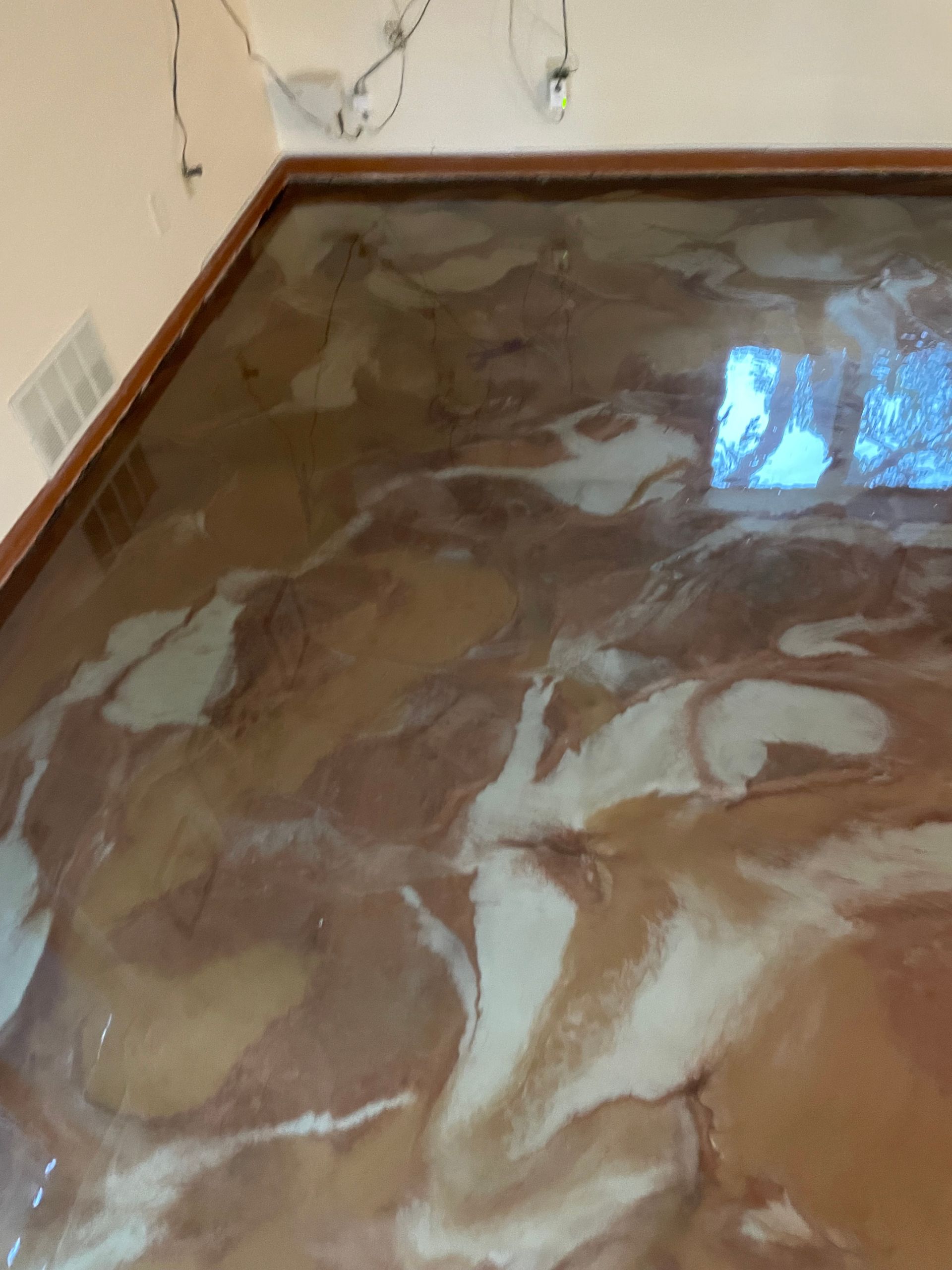 Metallic epoxy floor with brown, beige, and white swirls in a room.